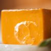 Sacral Chakra Soap, with bubbles sitting on a stone soap dish with herb leaves | Shine Body & Bath